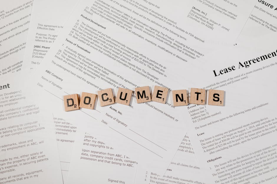 Top view of scrabble tiles spelling 'DOCUMENTS' on various contracts and agreements.